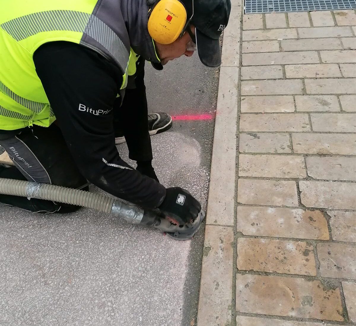 Randbearbeitung beim Asphalt Grinding – Randbearbeitung von Hand – die Kante wird mit der Handschleifmaschine nachgearbeitet
